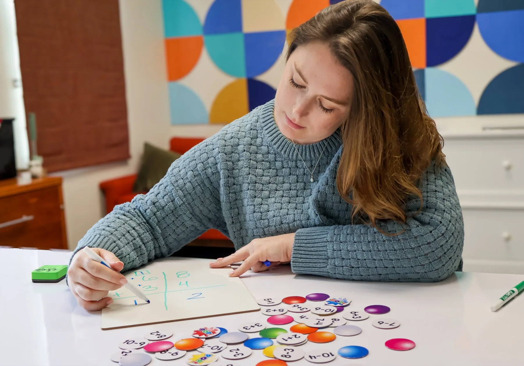 An educational therapist working one-on-one with colorful math manipulatives at a desk.